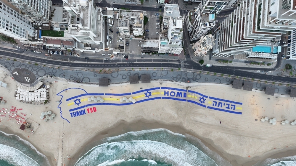 Tel Aviv’de ABD Büyükelçiliği karşısında dev bir karşılama etkinliği düzenleniyor. Üç futbol sahası uzunluğunda alana yayılan büyük çaplı enstalasyon, ABD Başkanı Donald Trump’a teşekkür mesajı taşırken, serbest bırakılanların dönüş yolunda helikopterlerden görebilmesi amacıyla tasarlandı.