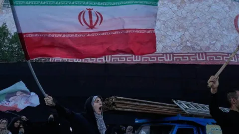 ABD ve İran bayrakları, ortasında bir anlaşma belgesi.