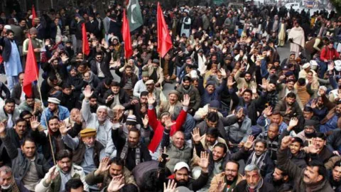 Pakistan'da bir grup işçi, kamu hizmetlerinin özelleştirilmesine karşı sloganlar atarak yürüyor.