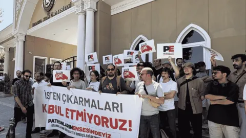 İstanbul Aydın Üniversitesi önünde toplanan akademisyenler pankart açarak slogan atıyor.